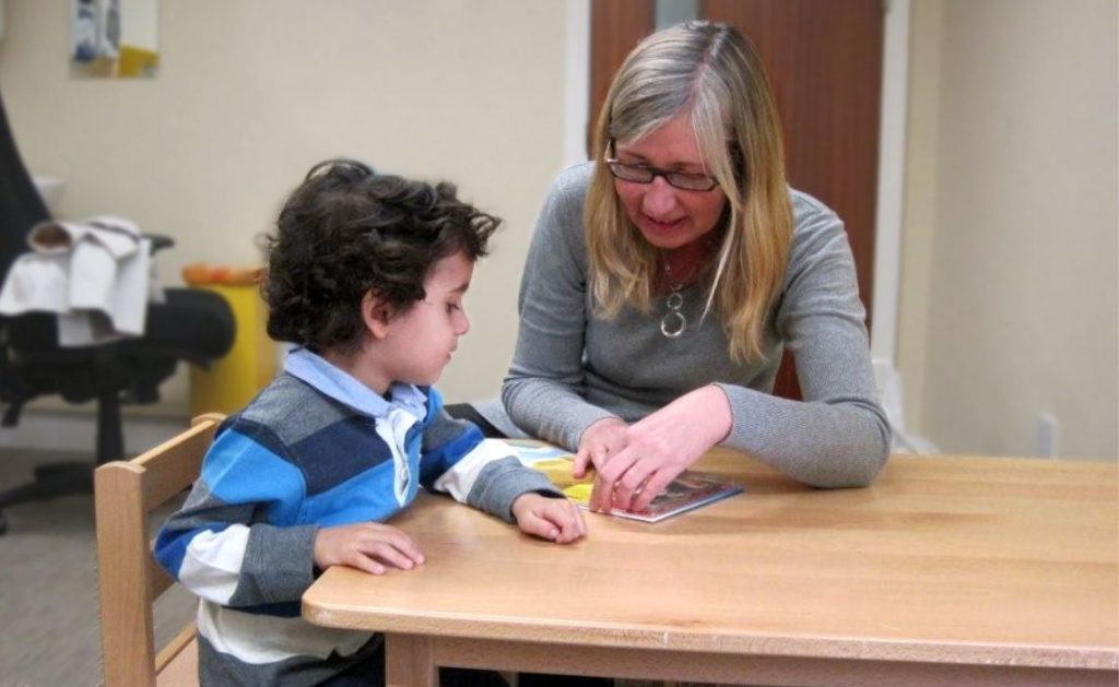 Anna Koppenhout speech and language therapist with a child during a therapy session.